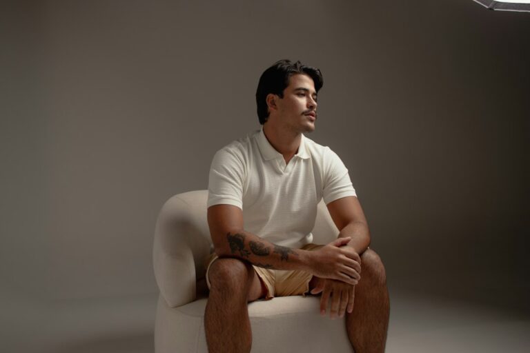 Man wearing a white polo shirt in a clean menswear editorial setting