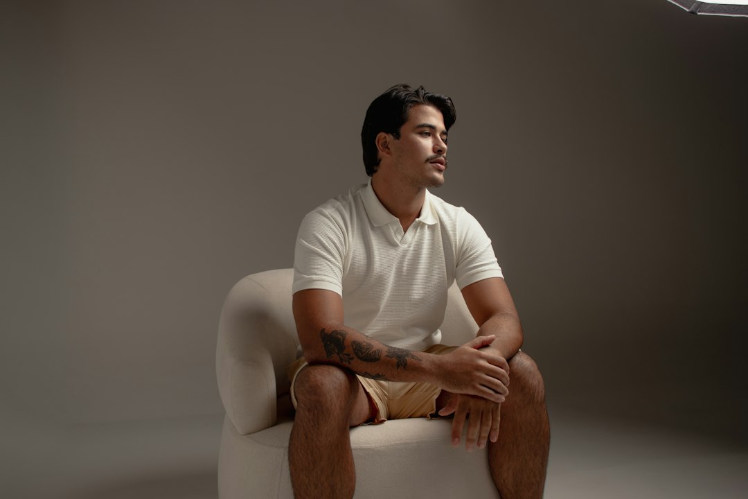 Man wearing a white polo shirt in a clean menswear editorial setting